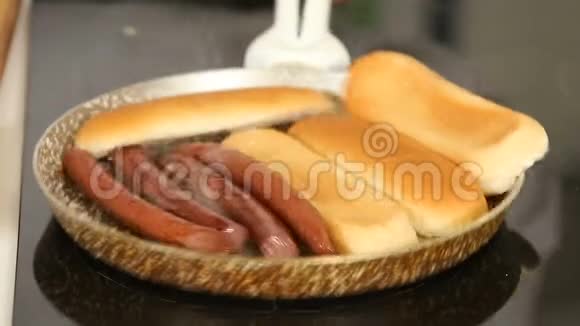 在煎锅上烤香肠和面包同时煮自制热狗视频的预览图