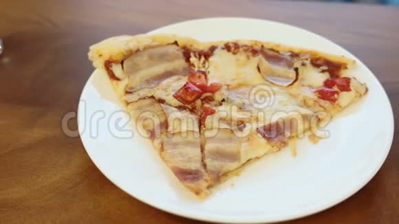 在木桌上的白色盘子上配上培根和甜椒的披萨片视频的预览图