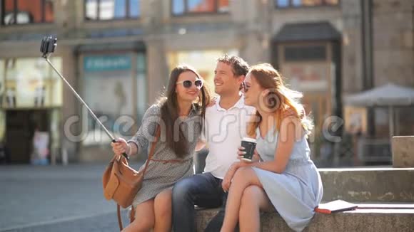 在阳光明媚的夏日一群年轻人在城市广场上使用智能手机户外活动两个女孩和视频的预览图