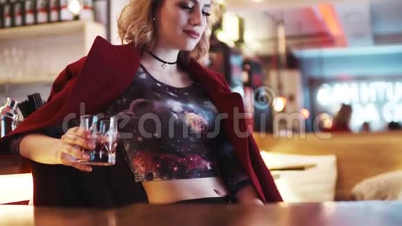 漂亮的女孩红唇穿着紧身布拿着酒吧旁边的鸡尾酒调情的样子搜寻视频的预览图