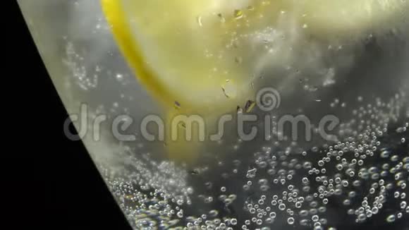 在旋转中加入冰块和柠檬的杯子特写镜头视频的预览图