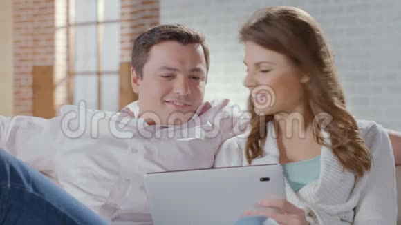 幸福的一对夫妇坐在沙发上用平板电脑网上购物视频的预览图
