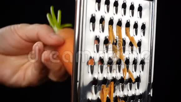 在黑色背景上的金属研磨器上擦胡萝卜视频的预览图