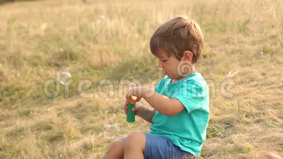 日落时玩肥皂泡的小男孩视频的预览图