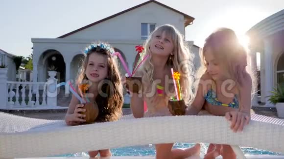 孩子们在游泳池里享受名人假期孩子们手里拿着鸡尾酒在游泳池里泼水富有视频的预览图