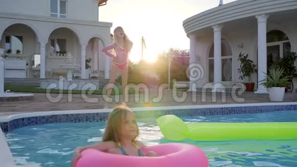 小女孩穿着游泳池边的泳衣跳舞可爱的孩子在充气环泳池在阳光下游泳视频的预览图