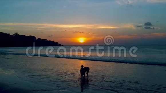 在巴厘岛印度洋日落时分父亲和一个儿子视频的预览图