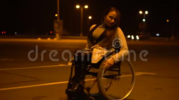有魅力的残疾女孩坐在轮椅上等待出租车晚上在购物中心附近停车视频的预览图