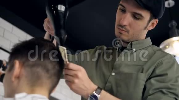 一位发型师用吹风机梳男客户的头发视频的预览图