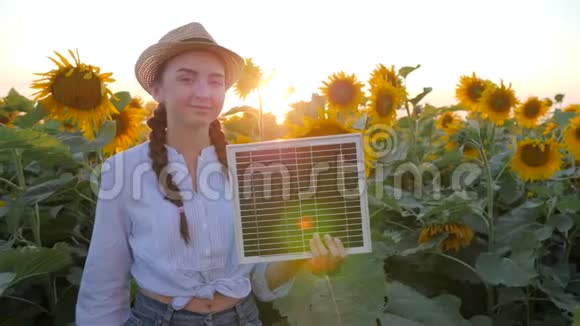 女孩手持太阳电池板靠近向日葵并展示手势如环保资源视频的预览图