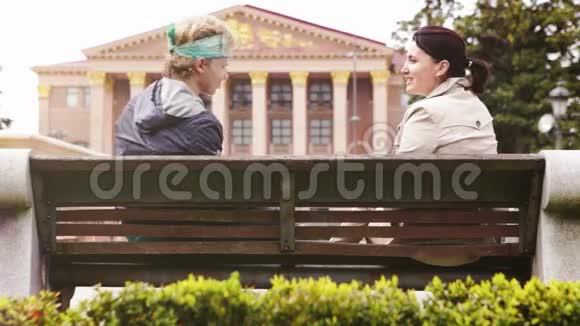 年轻人和一个女人坐在长凳上愉快地交谈视频的预览图