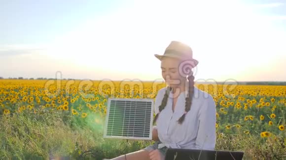 女孩在露天佩戴太阳能电池板女性在带笔记本充电器的背光中视频的预览图