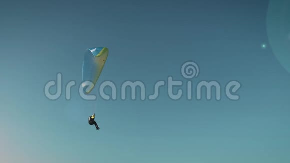 滑翔伞那个女人在单调的蓝天背景下在滑翔伞上飞行视频的预览图
