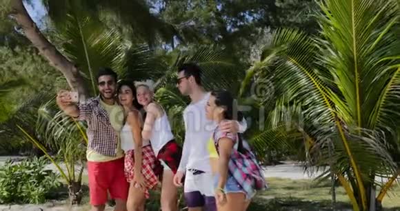 人们在棕榈树下的海滩上的手机拍照热带假日的男女游客视频的预览图