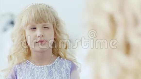 一个穿着漂亮头发的漂亮裙子的金发女孩看着镜子里的自己幼儿园毕业舞会视频的预览图