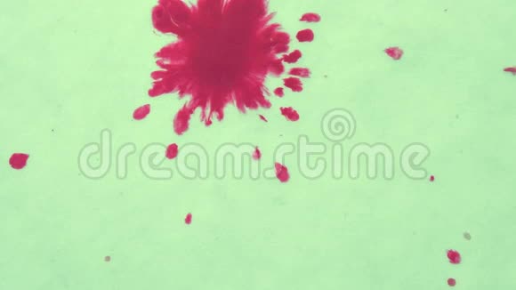 油墨点的红色流动在白色表面特写视频的预览图