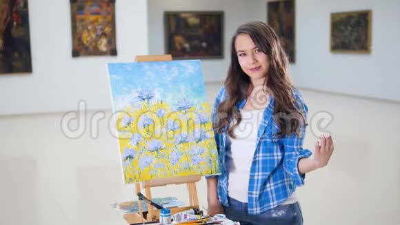 美丽的女孩站在画的旁边肖像视频的预览图