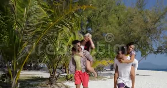 女孩骑着男人回海滩两对欢愉的情侣在夏日度假微笑游客视频的预览图