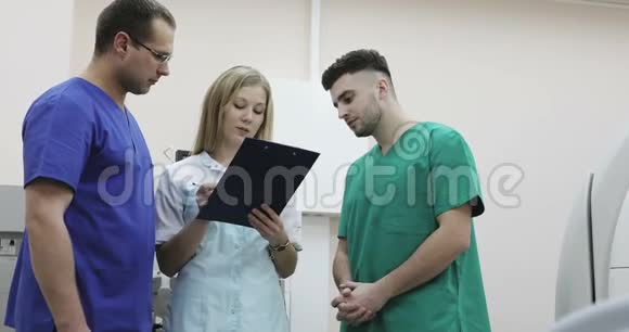 4三个穿着医疗服的年轻医生在诊所里交谈视频的预览图