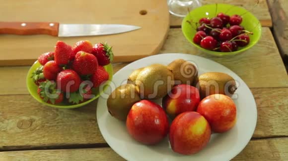 新鲜水果猕猴桃桃子草莓和樱桃放在木桌上视频的预览图