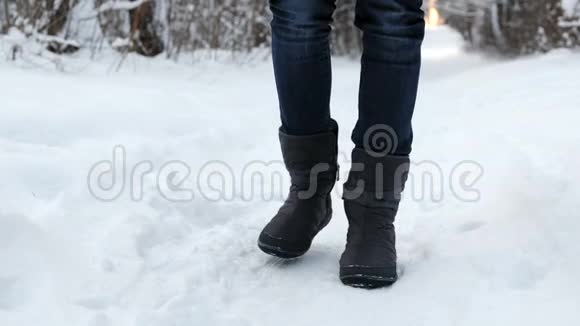 一个穿着靴子的女人冻僵了的腿在雪中从寒冷中跺脚视频的预览图