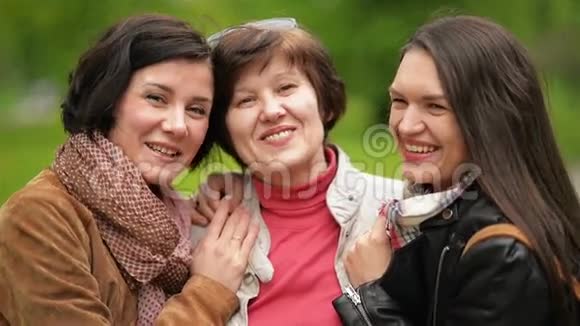 两个微笑的姐妹在户外拥抱和亲吻他们的母亲幸福的家庭一起在公园里度过时光视频的预览图