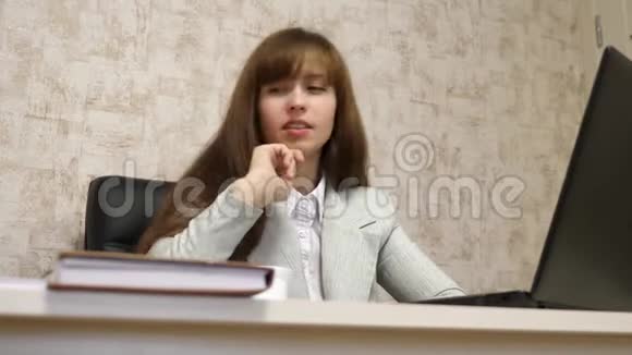 漂亮的女商人坐在办公室的椅子上在笔记本电脑和纸质文件上在线工作年轻女子视频的预览图