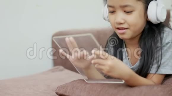 亚洲小女孩使用白色无线耳机和透明垫的未来技术移动应用概念视频的预览图