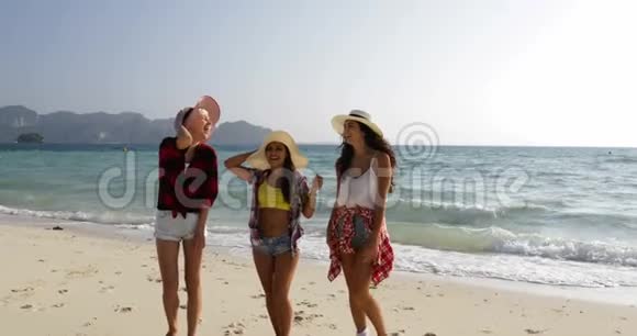 女人在沙滩上从水中漫步少女游客在交流时开心地笑着视频的预览图