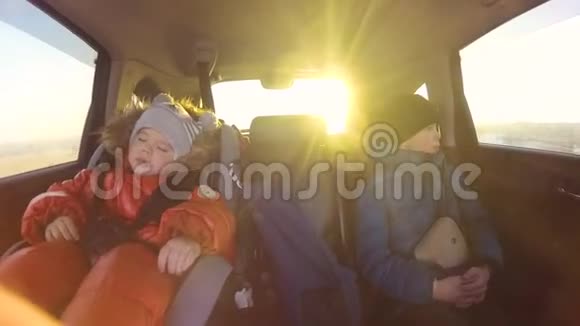 孩子们坐在车里太阳透过玻璃的光线慢动作视频的预览图