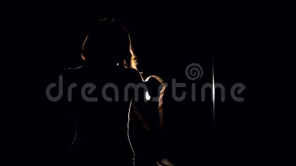 一个女孩在黑暗中用一个投影仪积极地打拳击的中镜头视频的预览图