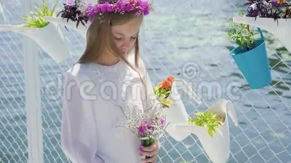 可爱的女孩穿着白色刺绣手里拿着野花看着相机4K视频的预览图