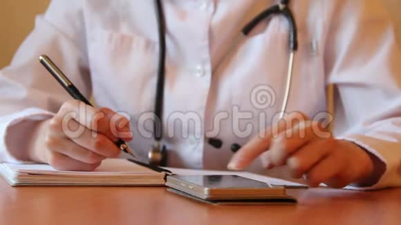 女医生在desc的笔记本上写字专业人士正在使用智能手机搜索数据库中的信息视频的预览图
