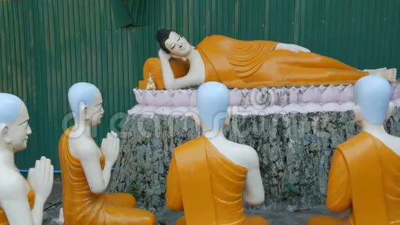 在泰国的一座寺庙里一尊倾斜的佛陀和他周围的朝圣者的雕像视频的预览图