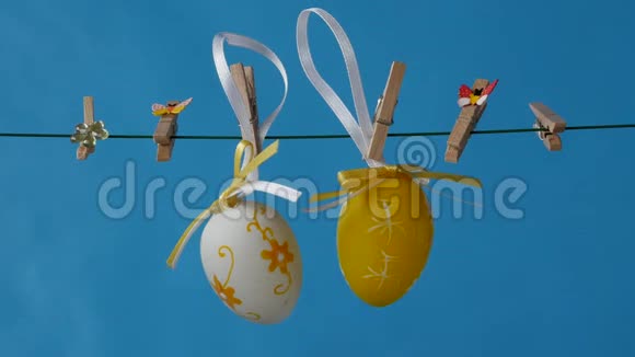 复活节彩蛋挂在蓝色背景的晾衣绳上视频的预览图