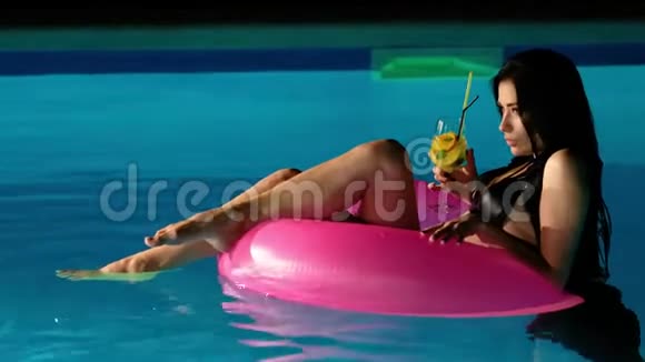 年轻美丽的黑发女人在游泳池里喝新鲜的鸡尾酒视频的预览图