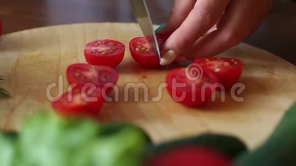 一位女厨师的特写在木制砧板上切下一个成熟的番茄视频的预览图