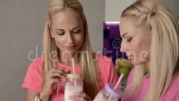 金发碧眼的双胞胎姐妹喝一杯带管子的奶昔视频的预览图