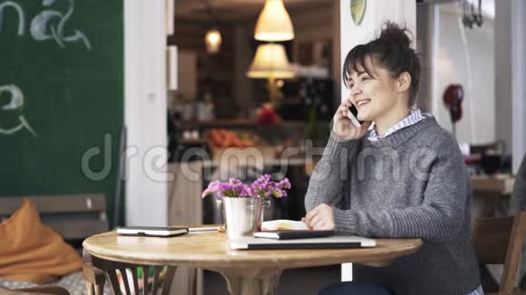 一位年轻女子在一家咖啡馆学习并在电话中交谈视频的预览图