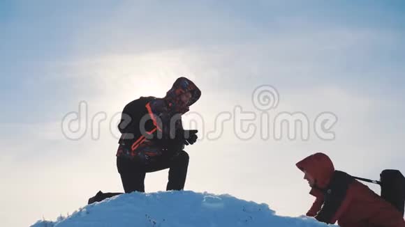 团队合作两个旅游徒步旅行者伸出了援手成功赢得冬天到达山顶登山游客视频的预览图