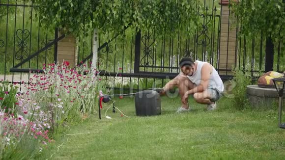 工人从割草机的袋子里摇着把草倒进手推车里花园草地草坪修剪园林夏季工程视频的预览图