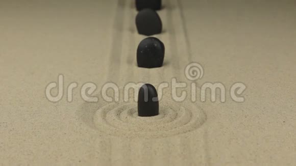 一块黑色的石头站在一圈沙子里视频的预览图
