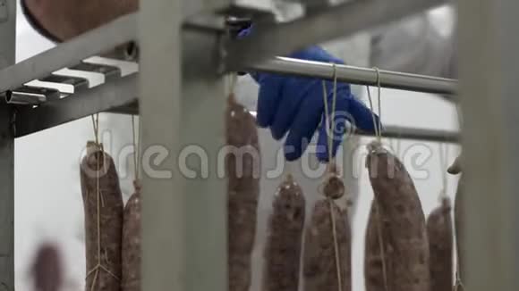 戴手套的男工在架子上分发香肠肉类加工工厂工艺视频的预览图