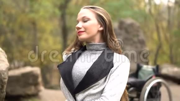 秋天公园里坐在石头上的轮椅上有魅力的女孩残疾人休闲视频的预览图