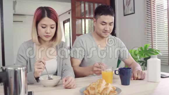 快乐甜蜜的亚洲夫妇在早上醒来后吃早餐牛奶中的谷类食品面包和喝橙汁视频的预览图