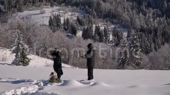 快乐的年轻家庭正在雪地里玩得很开心他们扔雪和笑他们也快乐地掉进了雪里视频的预览图