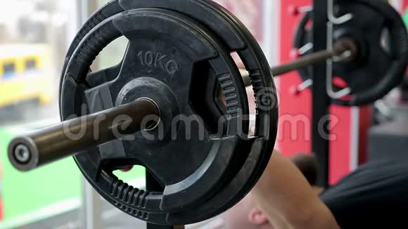 强壮的男性健美运动员在健身房里用沉重的杠铃做长凳按压运动视频的预览图