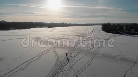 渔夫走在结冰的河上从上往下看雪中行走的人的影子空中观景4K视频的预览图