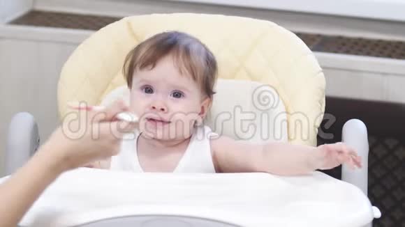 宝宝坐在高椅上吃汤匙口水和微笑的粥视频的预览图