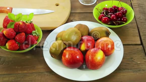 碗里的新鲜水果猕猴桃桃子草莓和樱桃放在木桌上视频的预览图